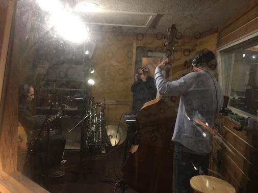 June 04, 2019 The view from one isolation booth to another. (L-R) Andy Brown guitarist, Bill Klewitz photographer, Dennis Carroll bassist. www.ratpackjazz.com